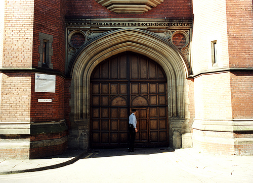 A person standing in front of a large wooden door AI-generated content may be incorrect.